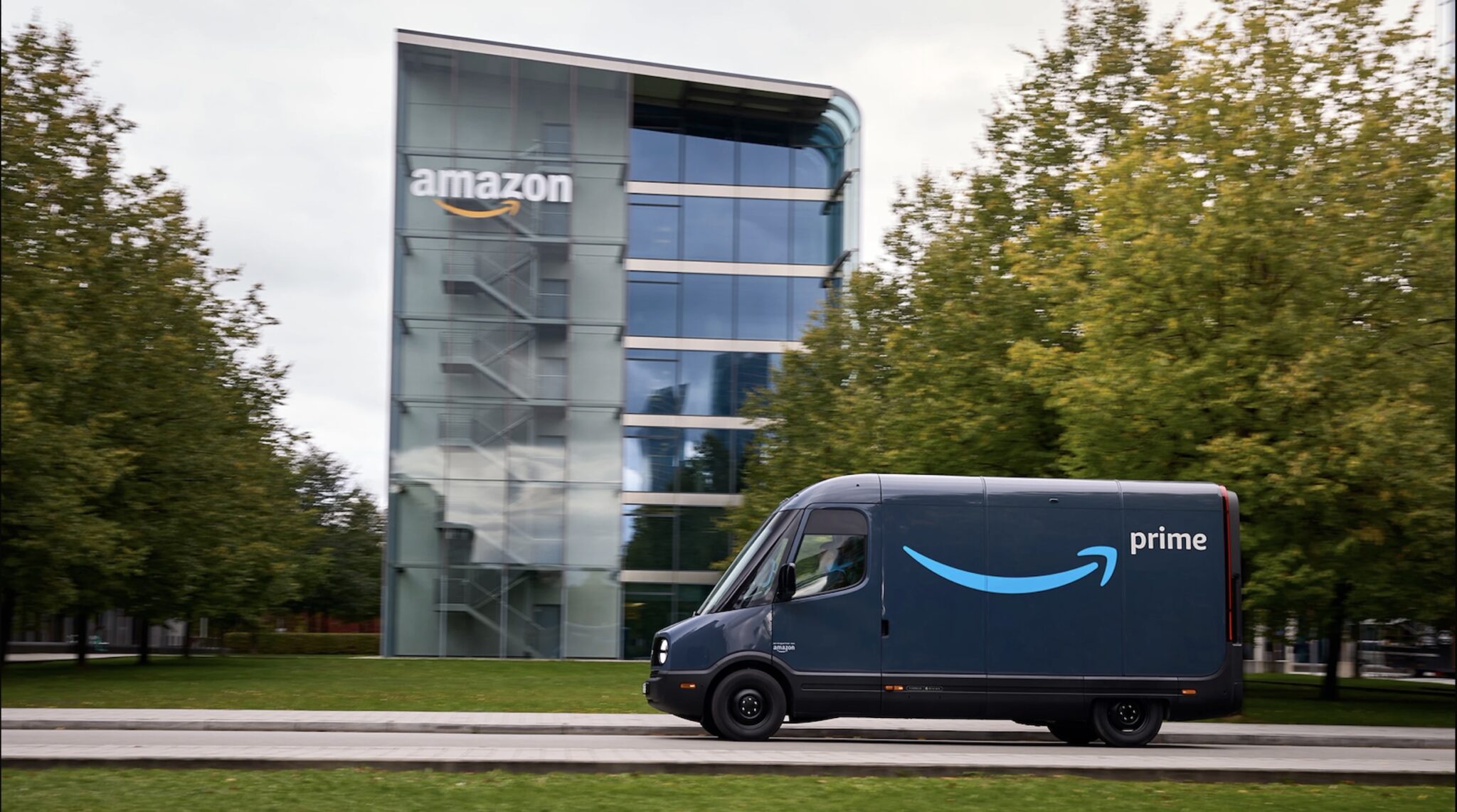 A commercial electric delivery van on the road past a corporate campus