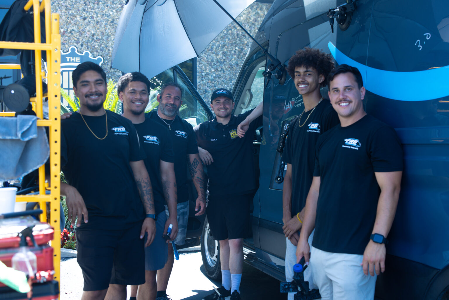 A team of FRS reconditioning technicians at a fleet depot with a commercial van behind them