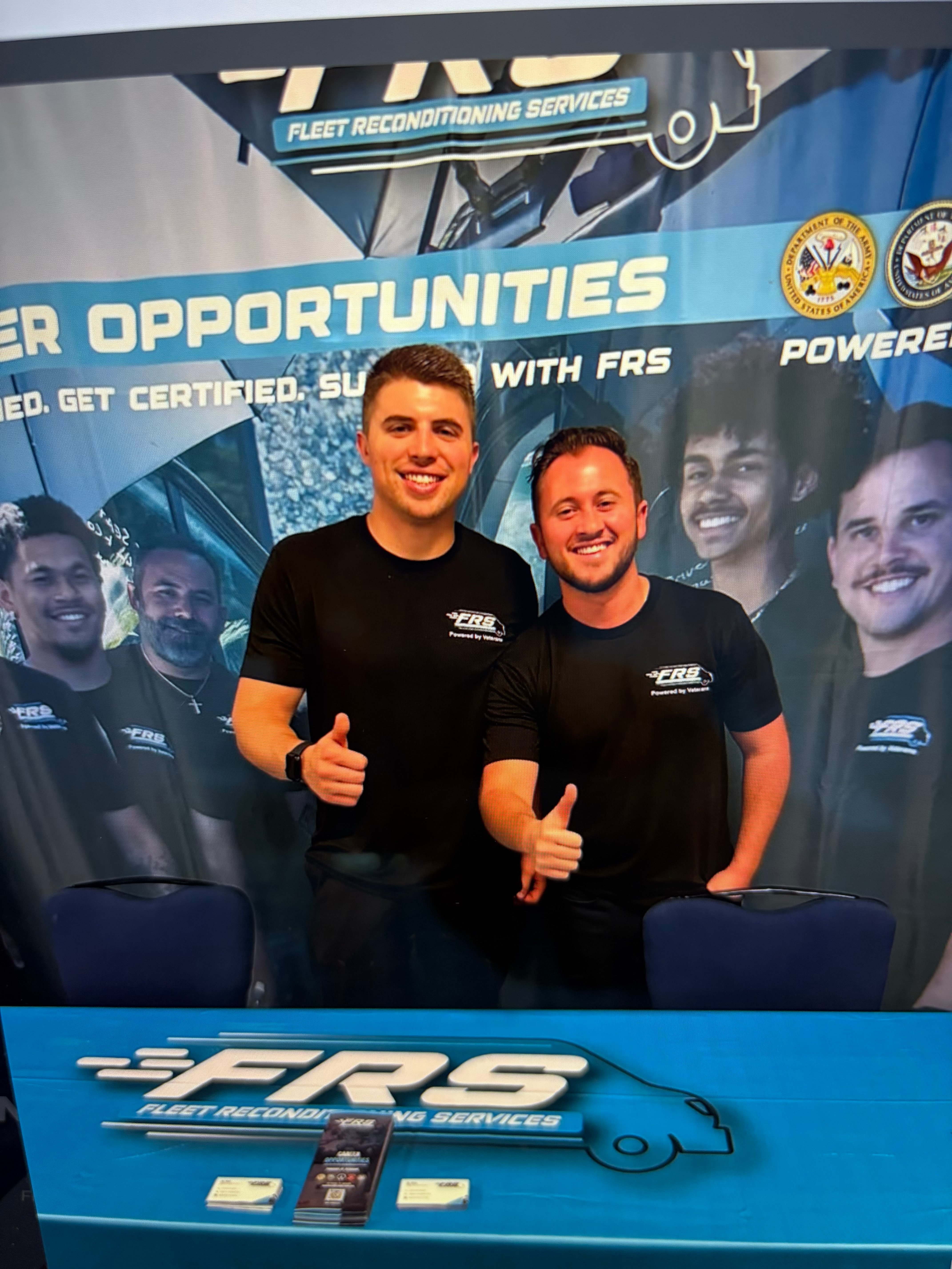 Two FRS leaders in Powered by Veterans apparel in front of a career opportunities banner