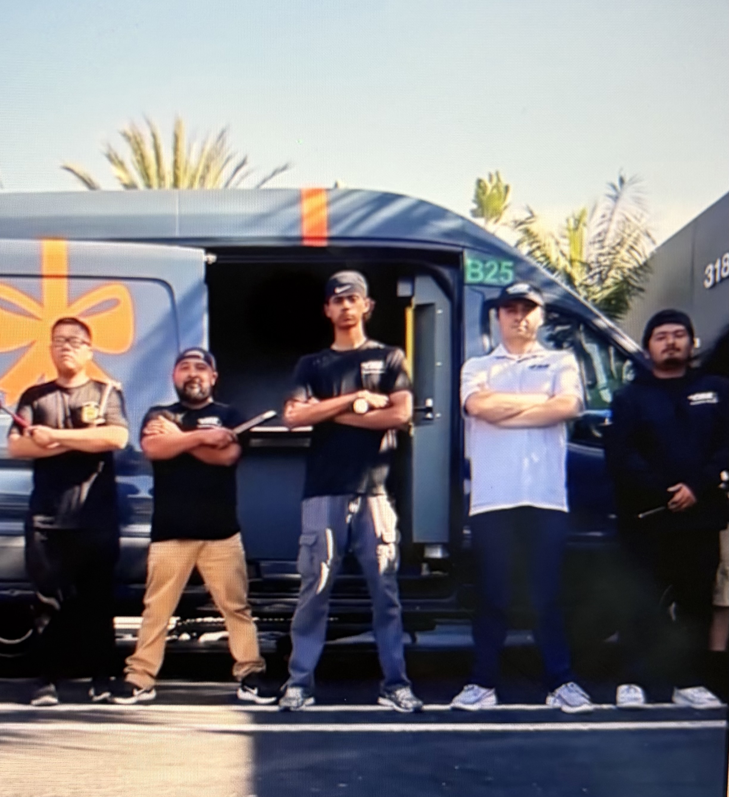 Five FRS technicians standing confidently with arms crossed in front of a delivery van