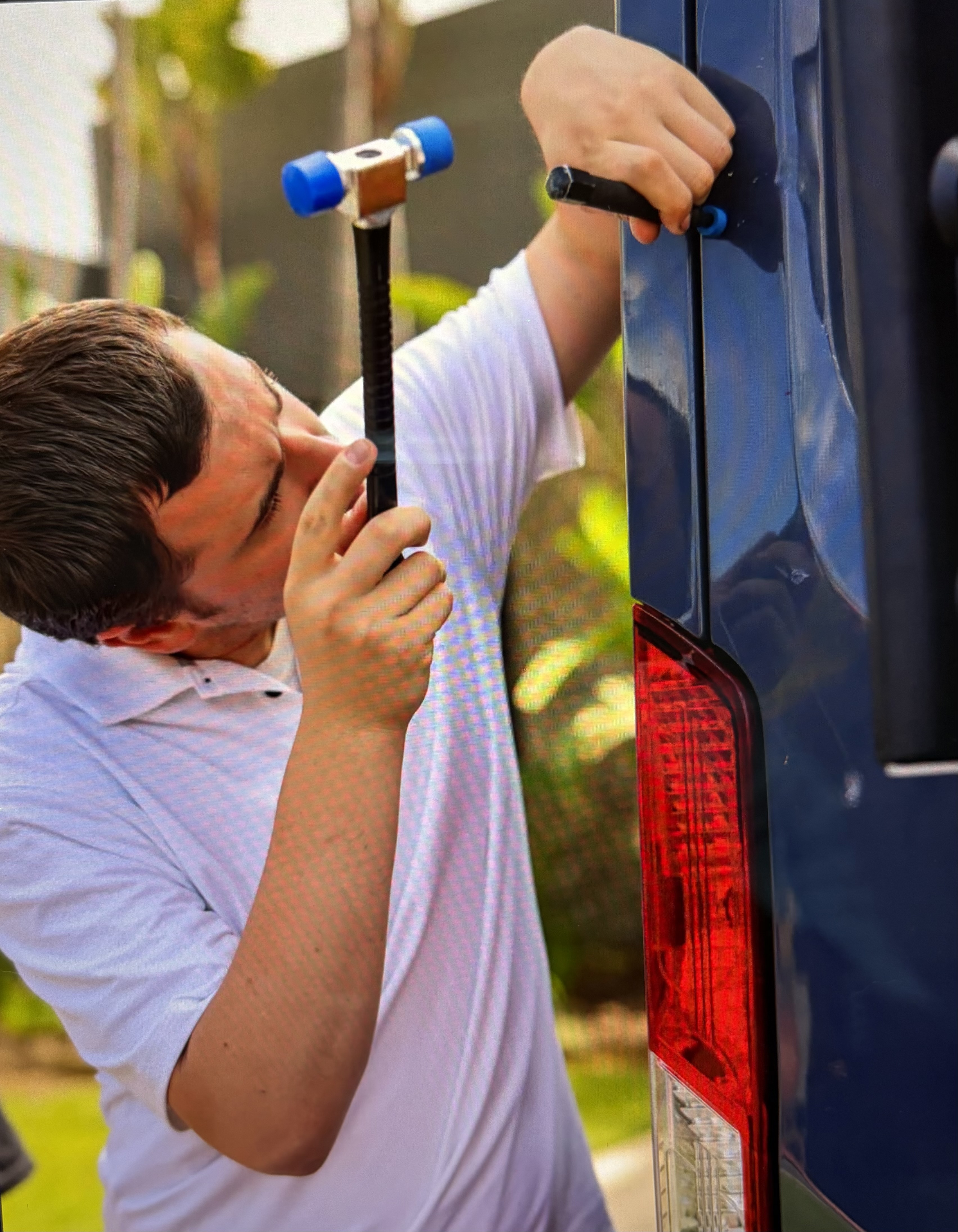 Close-up of an FRS technician using a slide-hammer tool for paintless dent repair on a van panel