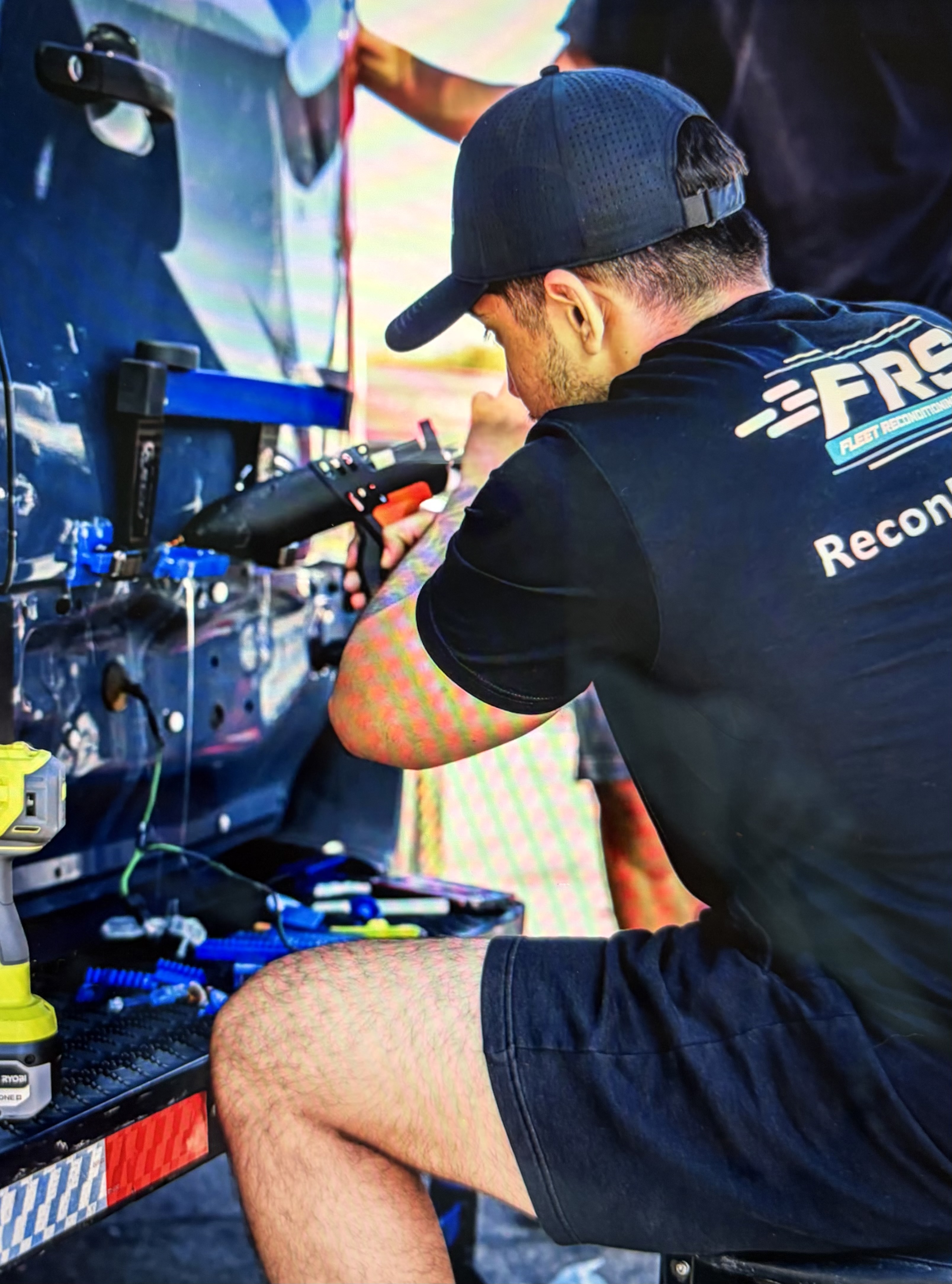 An FRS technician reconditioning a van panel with a specialized repair tool